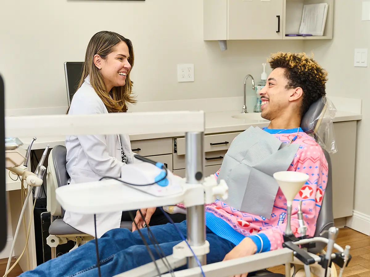 Dr. Laura Galiazzo talking to a dental patient sitting in a dental exam chair at Advanced Brookline Dental in Brookline, MA.